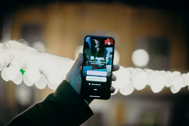 A hand holding a smartphone displaying an app login screen with a vibrant bokeh light background. Four ways to arrange identity and access compared: local accounts, a password manager, SSO, and provisioning