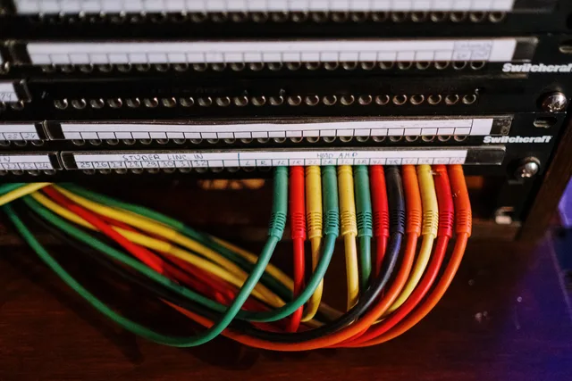 Close-up of colorful patch cables connected to a network panel with labels, indoors. Network security for small business: separation, router settings, and quarterly checks